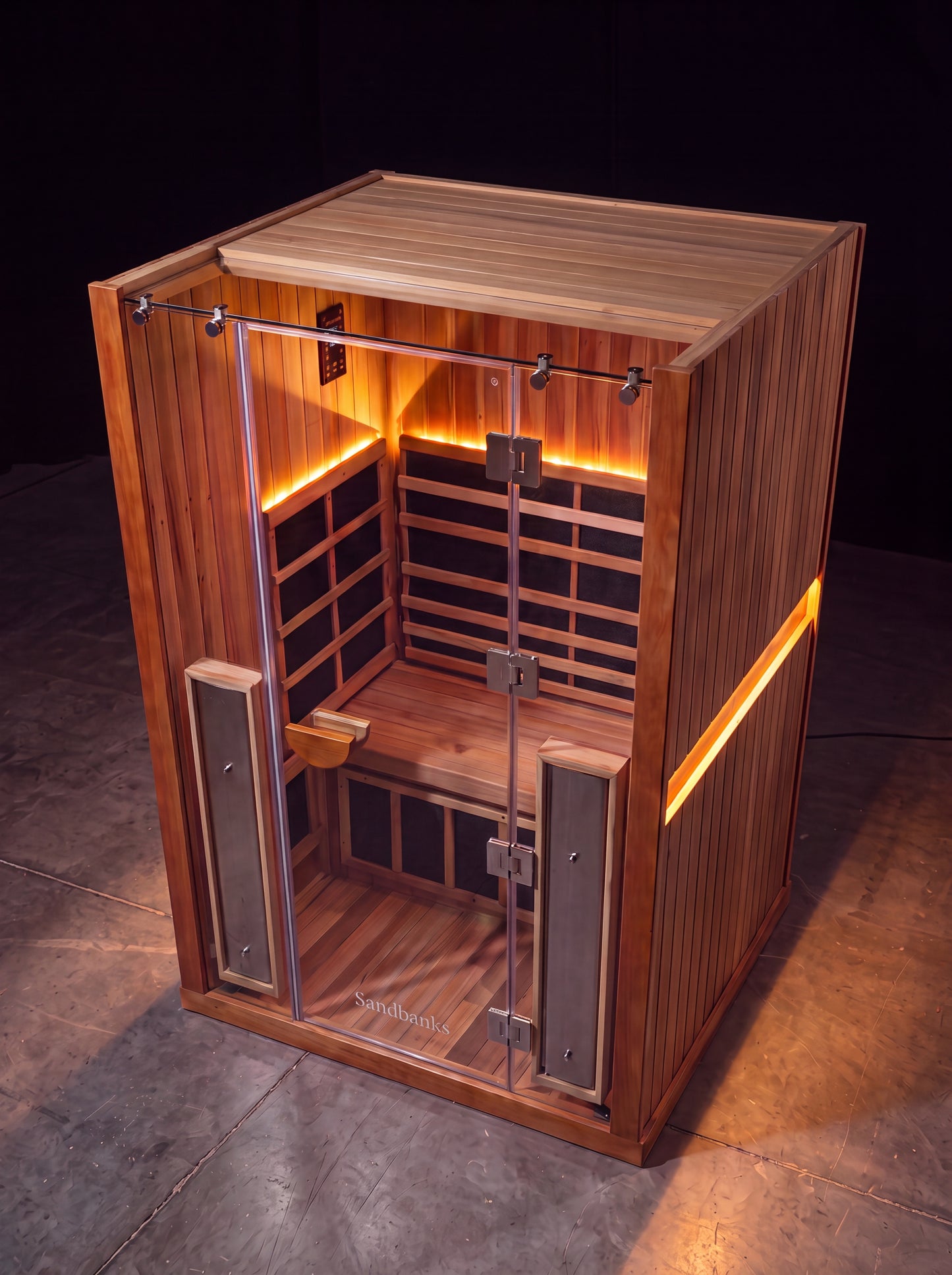 Solas Two infrared sauna — red cedar cabin with warm amber interior glow and Sandbanks etched glass door